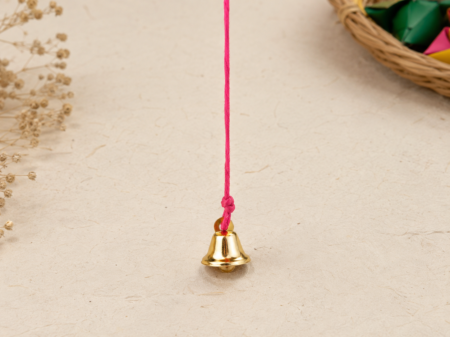 The pink thread tied to the small brass bell with a firm knot