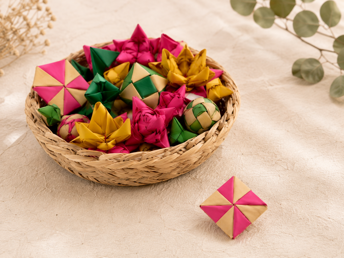 A basket full of different handmade ornaments — flowers, pinwheels, and stars — with one geometric ornament set aside